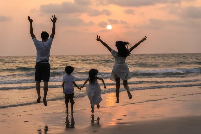 Une famille sautant de joie pendant le couché de soleil sur la plage