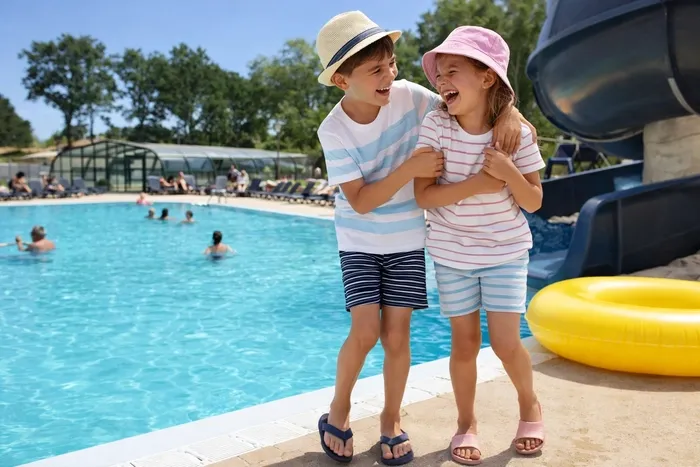 Deux enfant souriant et heureux se serrant dans les bras devant la piscine